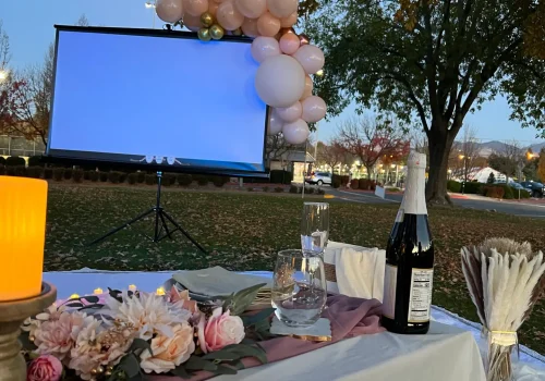 Outdoor birthday movie night setup with projector, candles, and balloons